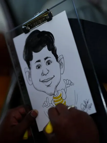 A caricature artist at work during a party. This is a unique and fun party favor, as guests get to take home a personalized and humorous drawing of themselves.