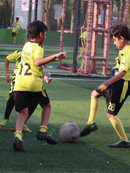Two players challenge for the ball, demonstrating the competitive but fair play I encourage in my academy.
