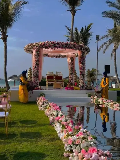 A picturesque beachside mandap with a mirrored aisle and pink floral decor, perfect for a destination wedding in Goa.