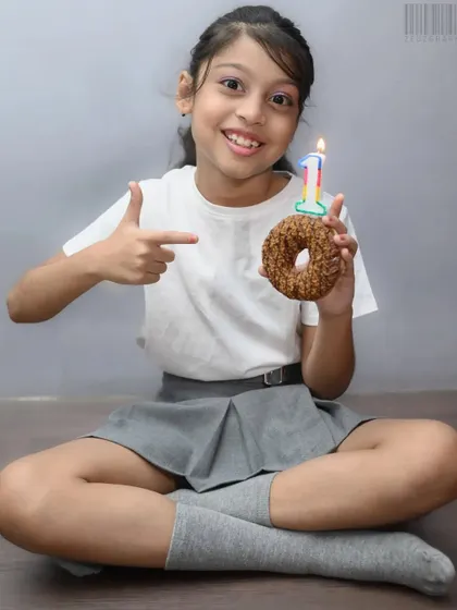 Celebrating a tenth birthday with a donut instead of a cake. This fun studio-style shoot captures the personality of the birthday girl, focusing on her happy expression as she points to the number 10 candle.