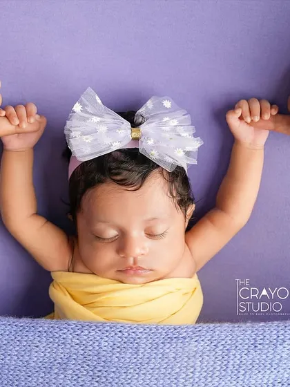 A newborn sleeps peacefully while holding onto her parents' fingers. This simple, powerful image shows the connection and trust between them.