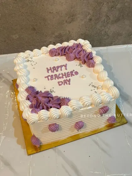 A square Teacher's Day cake with pretty purple and white piping.
