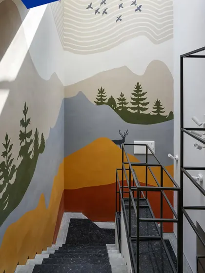 A custom mural adorns the staircase wall, turning a functional space into an artistic journey. The design depicts a serene mountain landscape, adding color and personality.