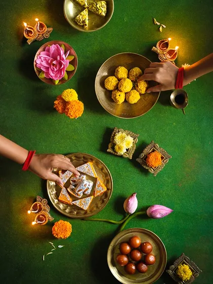 A top-down shot of hands sharing sweets during Diwali, capturing the spirit of community and celebration.