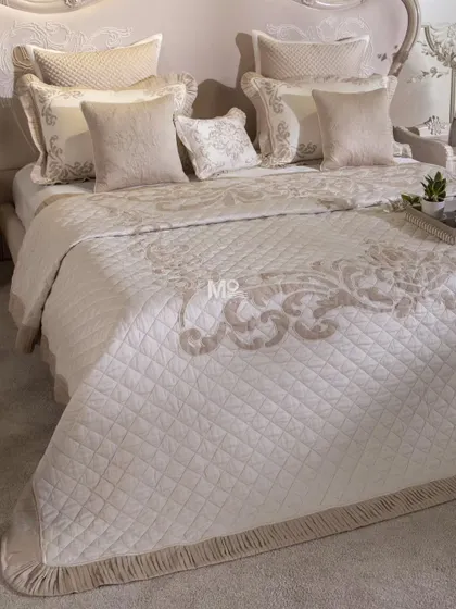 Our Magnolia-Themed Bed Cover Set, where muted tones meet meticulous craftsmanship. This piece features delicate aari and aada embroidery in geometric patterns, finished with classic ghimp detailing and soft pleated fringes.