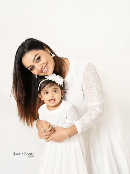 A mother and daughter sharing a happy moment in matching white dresses. This photo is a beautiful testament to their special bond.