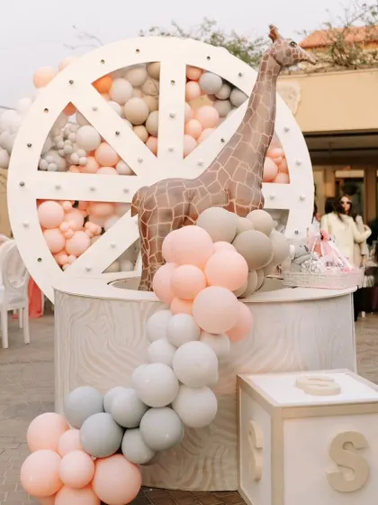 A large, illuminated wheel prop filled with balloons serves as a major focal point, complemented by a life-sized giraffe figure.