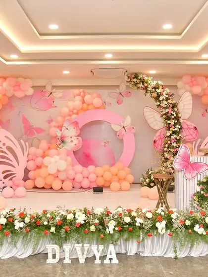 For this butterfly-themed birthday, I used a beautiful mix of real flowers and pastel pink balloons. The stage includes a large circular frame and butterfly cutouts to create a garden-like setting.