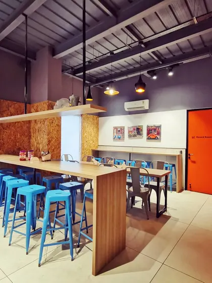 The employee cafeteria or breakout space, featuring high-top tables and bright blue stools. This informal setting provides a place for staff to relax and connect, fostering a positive workplace culture.