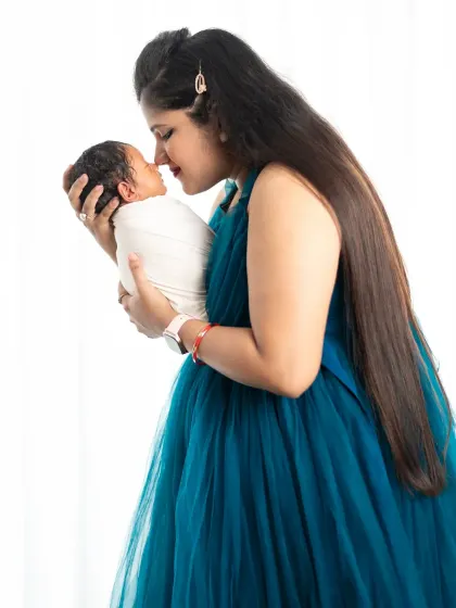 A mother's first portrait with her newborn. The simple white background and her flowing gown keep the focus on the pure love and connection between them.