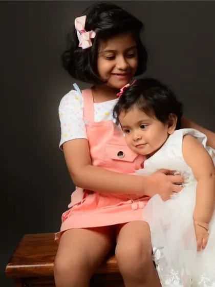 A touching moment between two sisters. The older sister gives her younger sibling a gentle hug during their studio photoshoot.