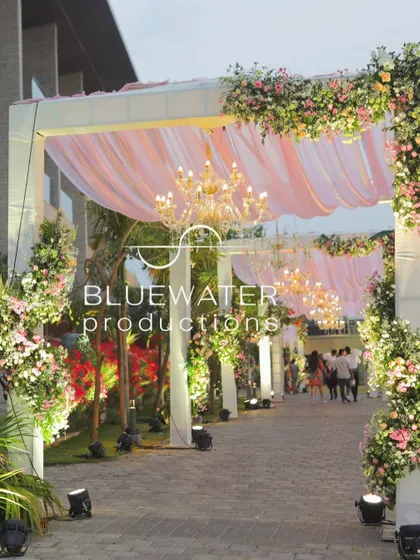 A romantic entrance for a garden wedding, with a floral-draped archway and hanging chandeliers creating a soft and inviting passage for guests.