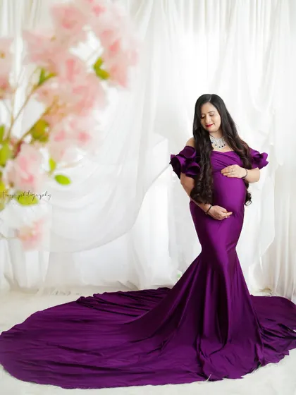 A regal portrait in a deep purple gown. The long train and elegant design of the dress create a stunning and dramatic look.