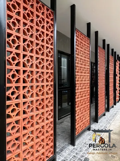 These freestanding jali panels act as space dividers along a walkway. Framed in black metal, the terracotta blocks add an earthy, textural element while maintaining a sense of openness and guiding movement through the space.