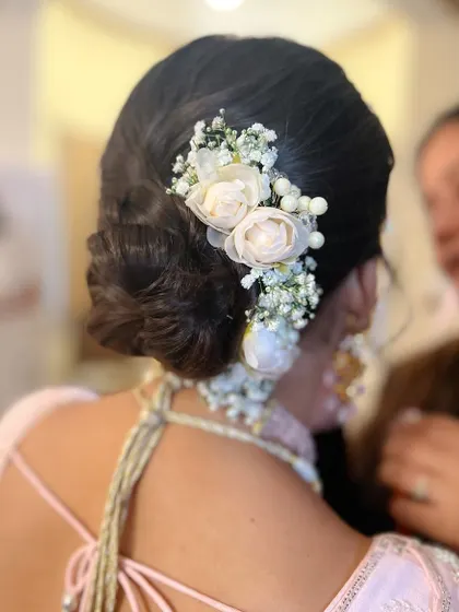 A soft and romantic low bun with a cascade of white flowers, perfect for a modern bride.