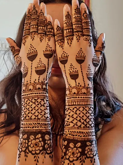 A fun and creative jhumka design. The pattern on the palms looks like chandeliers, while the arms have a classic net pattern.