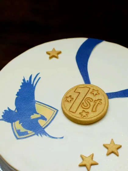 A detailed look at the edible gold medal and school emblem on the graduation cake. It's these personal touches that make a celebration cake truly memorable.