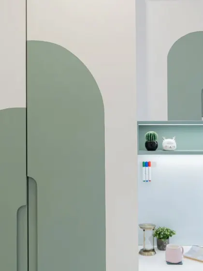 The study area features a built-in desk with a whiteboard surface and a custom wardrobe with unique arched-panel doors in a soothing green.
