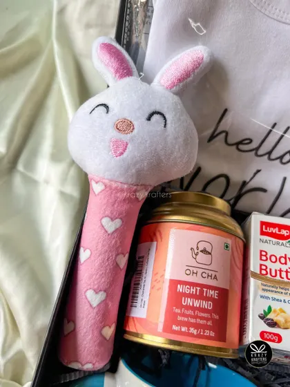 A close-up of the cute bunny rattle and 'Night Time Unwind' tea from our mom-to-be hamper, perfect for helping her relax.