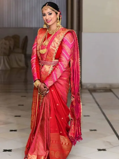 Royally dressed from head to toe. This bride's look is the epitome of South Indian grandeur, with a rich red Kanjeevaram saree, layered temple jewellery, and makeup that exudes elegance.