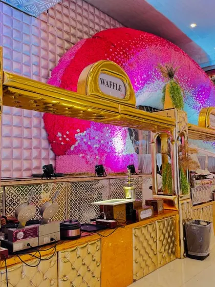 A grand waffle station with an elaborate floral backdrop and golden counter.