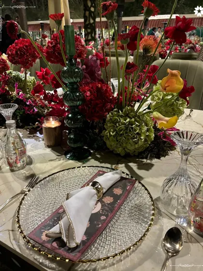 A close-up of the Sangeet tablescape, highlighting the vibrant floral arrangements and textured glassware. We layer different elements to create depth and visual interest in our table designs.