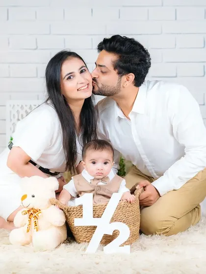 A half-birthday celebration for a six-month-old baby, with his parents giving him a loving kiss. A wonderful way to mark a special milestone.