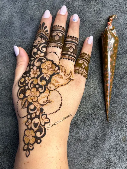 Another angle of the beautiful lovebird design, showcasing the fresh henna paste and the fine details of the pattern.