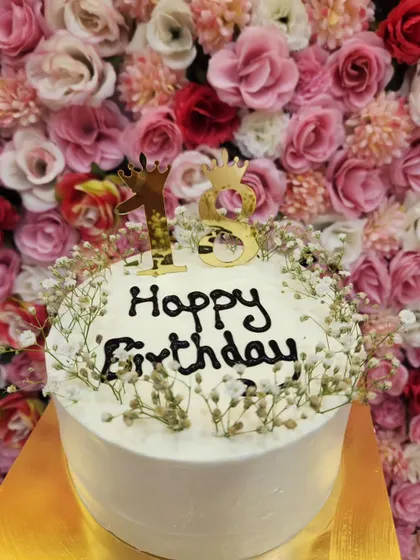 An elegant cake for an 18th birthday. The simple white frosting is decorated with baby's breath and a gold "18" topper for a sophisticated look.