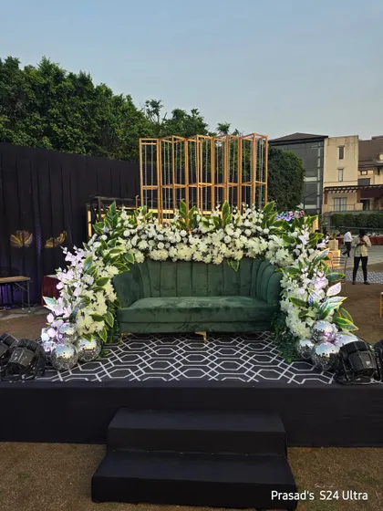 The full view of the green sofa photo area, set up on a low stage with a modern patterned floor.
