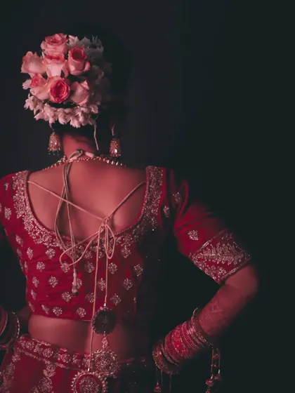 A detail-oriented shot focusing on the bride's intricate hairstyle, adorned with fresh roses, and the beautiful design of her blouse. We believe these details are essential to telling the full story of the bridal look.