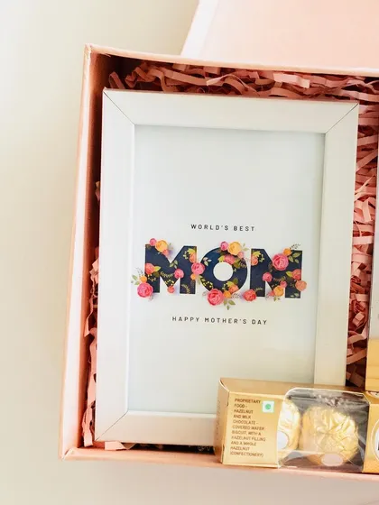 A detail shot of the 'World's Best Mom' frame inside the hamper, nestled in pink crinkle paper.