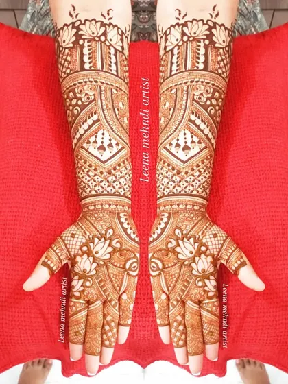This full-coverage design for a bride is filled with lotus motifs and detailed geometric patterns. The symmetry across both hands creates a balanced and harmonious look, extending beautifully up the forearms.