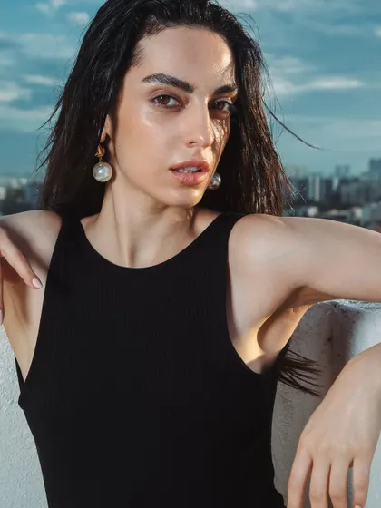 A beautiful portrait against the city skyline. The makeup remains fresh and luminous, perfect for an outdoor setting.