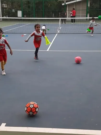 Two young players run with excitement on the court, embodying the spirit of our fun-based coaching.