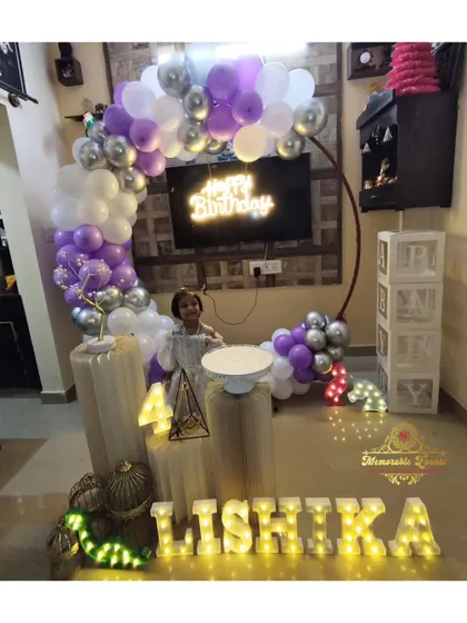 A child enjoying her birthday celebration in front of a purple and silver balloon ring decoration we set up.