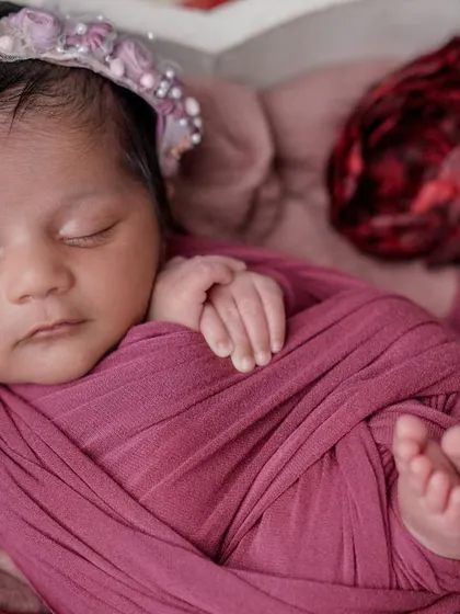 Dreaming of roses. This close-up shows the baby's tiny feet and hands, perfectly contained within a cozy magenta swaddle.