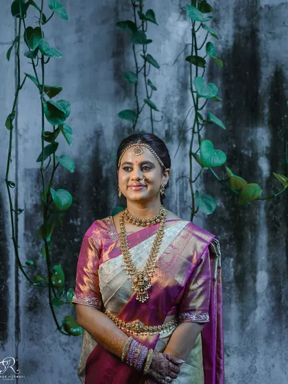 A beautiful portrait of a South Indian bride against a rustic, ivy-covered wall.