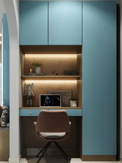 A compact study nook built into an alcove, featuring blue cabinetry and a backlit wooden shelf. It's a perfect example of our smart space planning.