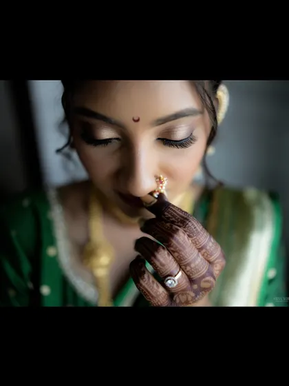 A timeless tale begins. This close-up captures the intricate details of a Maharashtrian bride, from the delicate nath to the beautiful mehndi and the soft, shimmering eye makeup.