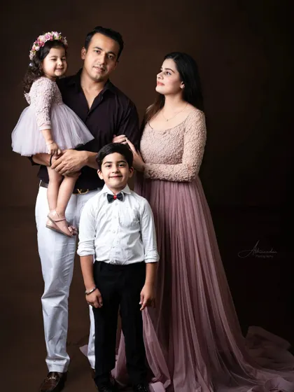 An elegant and formal family portrait against a classic dark backdrop.