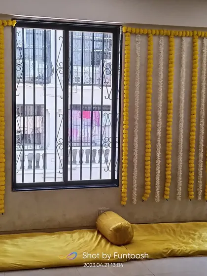 We can decorate any space. Here, we used marigold strings to brighten up the window area for a home Haldi ceremony.