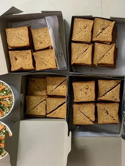 Packing up an order for a school picnic. Boxes of sandwiches and containers of fried rice, all ready for an early morning delivery.