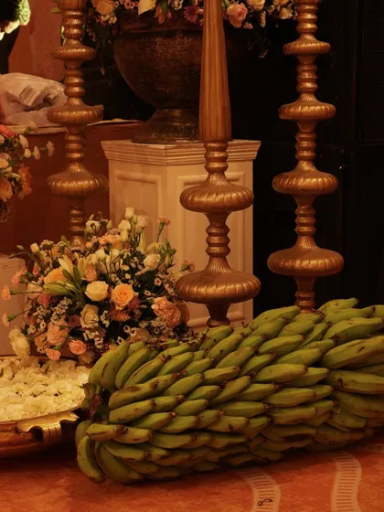 Traditional elements like brass decor and fresh banana bunches are incorporated into the decor, symbolizing prosperity and auspicious beginnings for the wedding festivities.