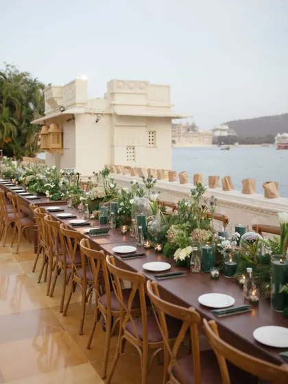 An elegant, long-table setup for a welcome dinner by the waters of Lake Pichola in Udaipur. We create relaxed yet sophisticated atmospheres for guests to mingle, with details like custom menus and ambient lighting.
