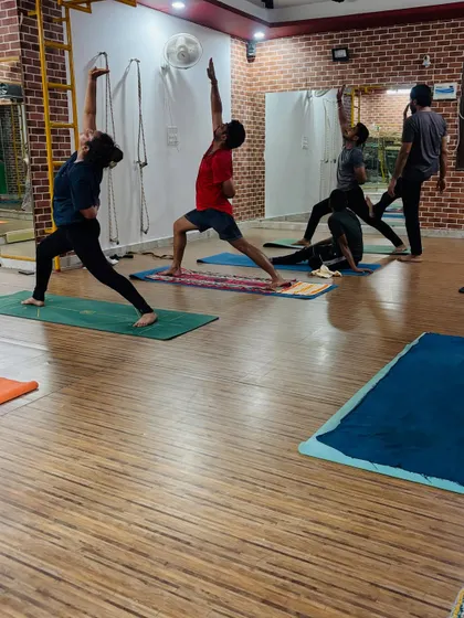 The energy of a group class, with students practicing variations of warrior poses and side angle poses, building heat and focus.