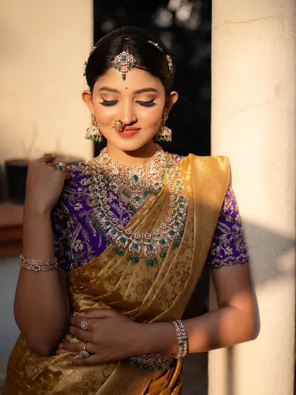 A serene portrait with eyes gently closed. The soft light and peaceful expression emphasize the elegance of the saree and the intricate diamond and emerald jewelry.