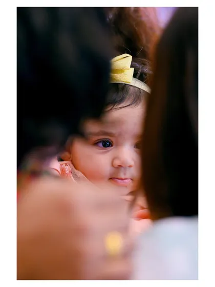 A creative shot taken through a gap, creating a sense of intimacy and drawing the viewer's eye directly to the baby's curious face.