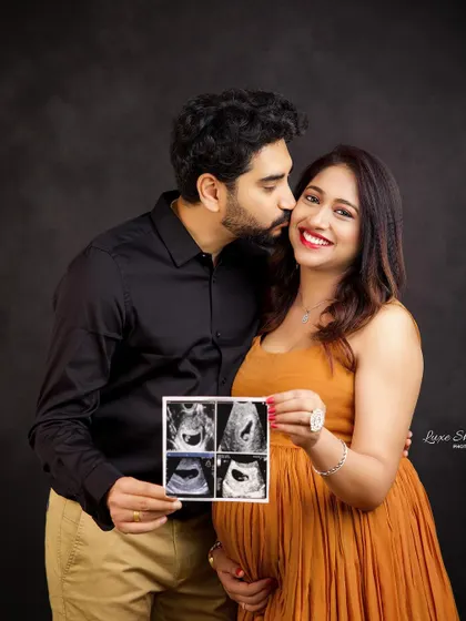 A joyful pregnancy announcement photo. The couple's happiness is contagious as they share their sonogram pictures in this lovely studio portrait.