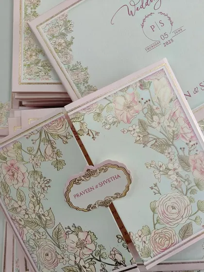 This pastel lotus-themed wedding card features a gate-fold design in soft blue and pink, with a gold-foiled nameplate.